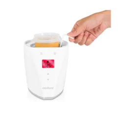 a hand pouring liquid into a container chauffe biberon + sterilisateur miniland voiture